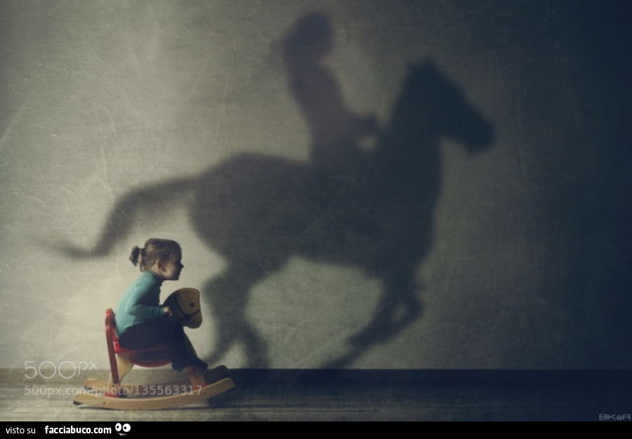Bimba sul cavallo a dondolo proietta ombra di donna a cavallo