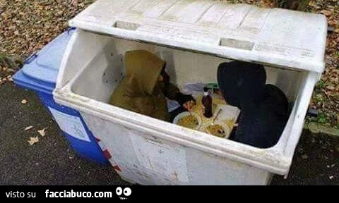 Uomini che mangiano dentro un cassonetto
